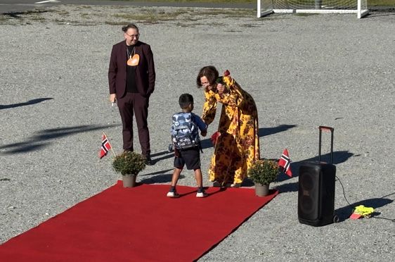 en person og et barn som står på en rød løper med en person i et plagg