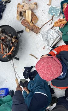 En gruppe mennesker i et snødekt område med et bål