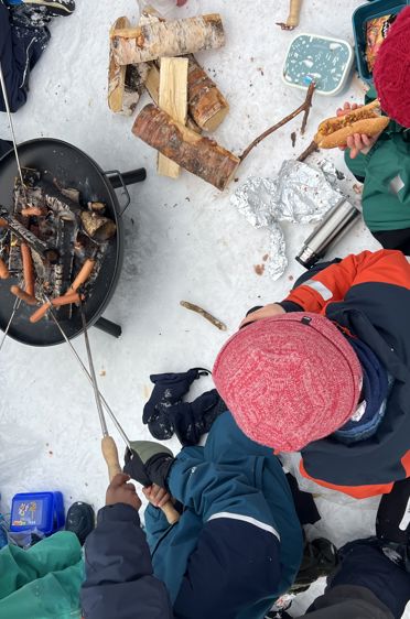 En gruppe mennesker i et snødekt område med et bål
