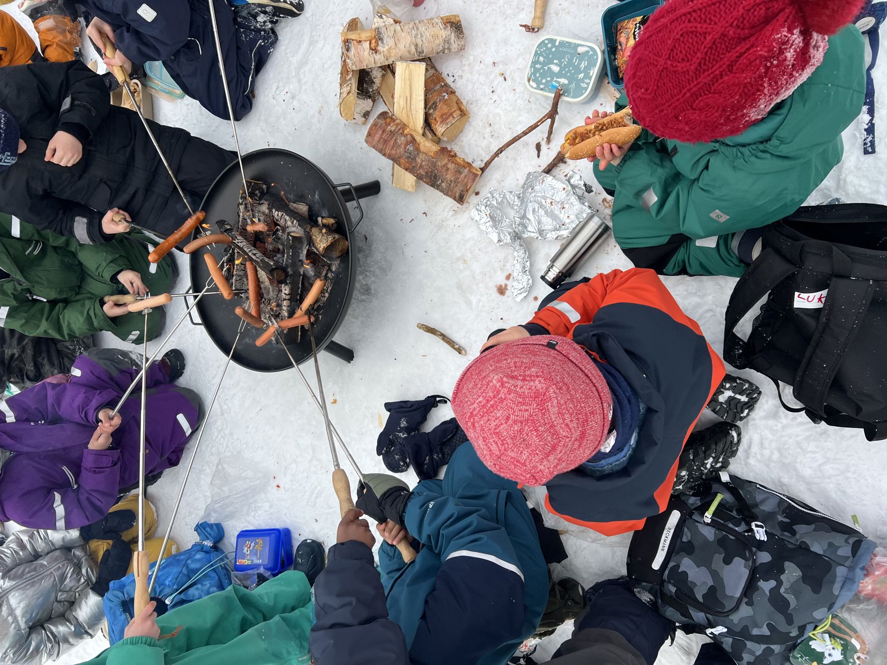 En gruppe mennesker i et snødekt område med et bål