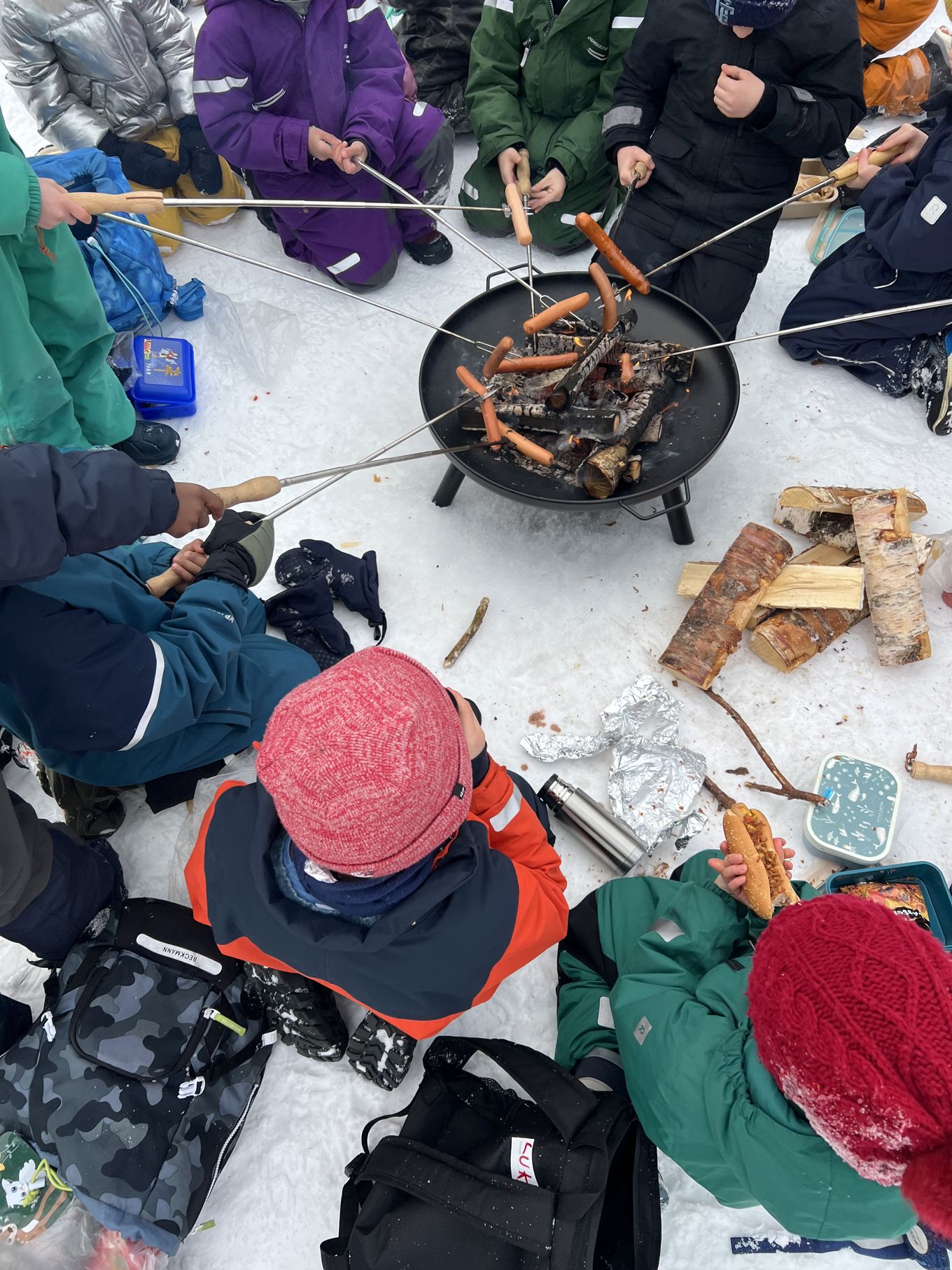 En gruppe mennesker i et snødekt område med et bål