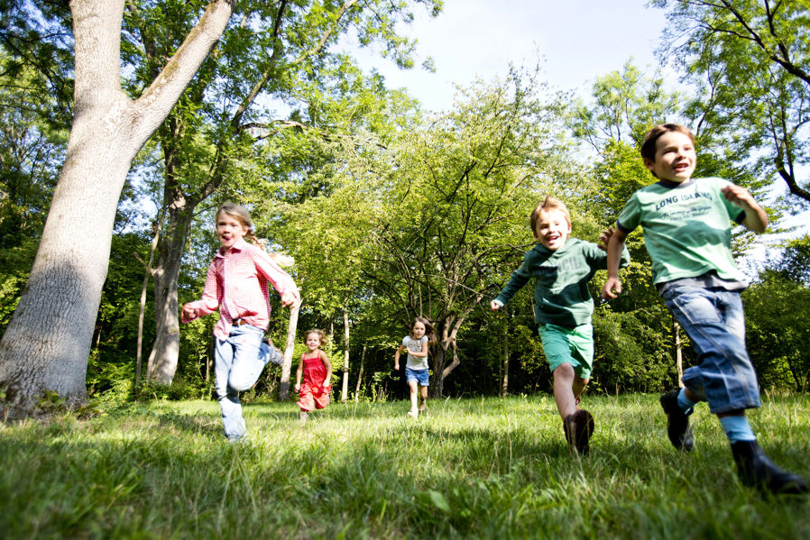 barn løper i gresset mot kamera